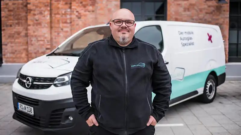 Autoglas-Monteur von nobleglass vor einem Fahrzeug stehend